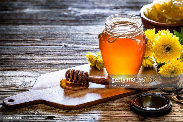 honey-jar-with-honey-dipper-shot-on-rustic-wooden-table-picture-id1093966734?s=612x612